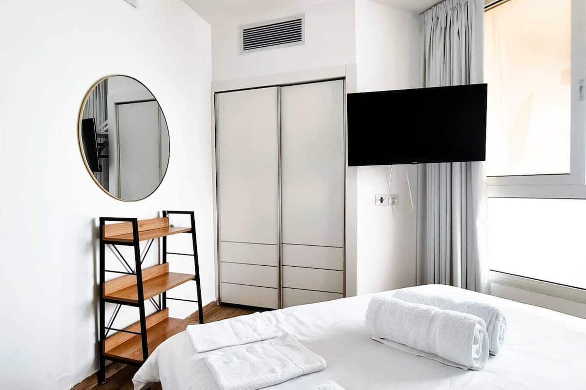 A hotel room with a bed, a TV, a wardrobe, and a mirror.