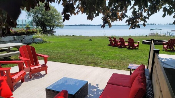 Ein Sitzbereich im Freien mit roten Adirondack-Stühlen, einer Korbsessel-Couch und einem kleinen Tisch.