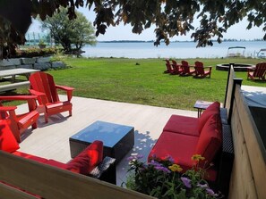 An outdoor seating area with red Adirondack chairs, a wicker sofa, and a small table.