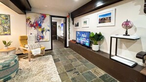 A hallway with a modern design, featuring a television, artwork, and a globe on a console table.