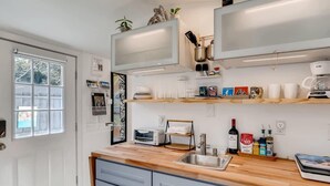 Eine moderne Küche mit Holzarbeitsplatte, integrierten Geräten und einem großen Fenster.