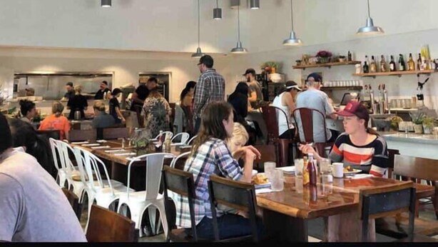 En rymlig restaurang med högt i tak, synliga takbjälkar och hängande lampor.