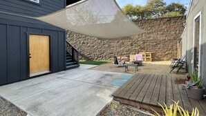 Une terrasse dotée d’une plateforme en bois, d’une zone en béton et d’un mur en pierre.