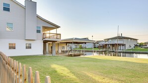 A residential property with a large lawn, a wooden deck, and a small dock by a body of water.