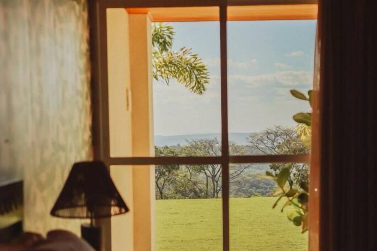 A room with a view through a glass door to a grassy area with trees.