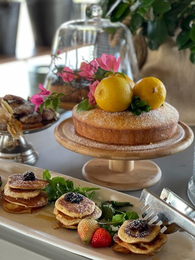 A dessert table with a cake, pancakes, and fruit.