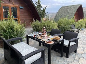 An outdoor dining area with wicker chairs and a table set with food and drinks. - Clean Bungalov Tatil Köyü (Ermenek)