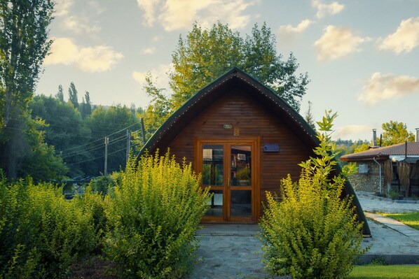 A wooden cabin with a stone pathway leading to the entrance, surrounded by lush greenery. - Clean Bungalov Tatil Köyü (Ermenek)