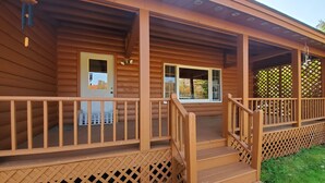 A wooden cabin with a porch, a front door, and a window. - White Mountains Vista Lodge (Warren)