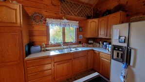 A wooden cabin kitchen with a sink, stove, and refrigerator. - White Mountains Vista Lodge (Warren)