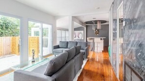 Ein modernes Wohnzimmer mit einem grauen Moduls Sofa, einem Glastisch und Holzboden.