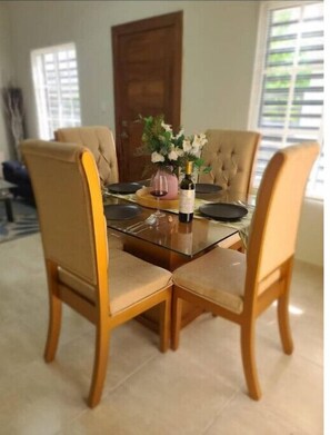 Una mesa de comedor con cuatro sillas, un jarrón con flores y una botella de vino.
