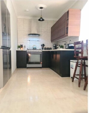 Una cocina moderna con una isla central, electrodomésticos de acero inoxidable y una silla de madera.