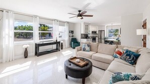 A spacious living room with a sofa, ottoman, and a ceiling fan. - Super Snapper OceanView Heated Pool, Tiki, Large Dock, Lanai (Marathon)