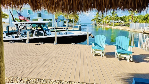 A wooden deck with a thatched roof, a boat docked, and a sign reading "The View". - Super Snapper OceanView Heated Pool, Tiki, Large Dock, Lanai (Marathon)