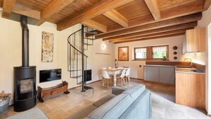 Een moderne woonkamer met een open haard, een spiltrap, een eethoek en een keuken.