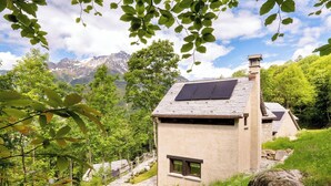 Una casa con fachada de piedra, una ventana pequeña y un panel solar en el techo.