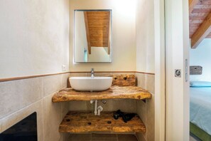 A bathroom with a wooden vanity, a white sink, and a mirror above it.