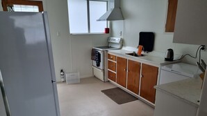 Ett kompakt kök med kylskåp, spis, ugn och träskåp.