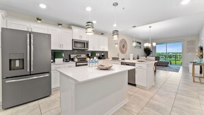 A modern kitchen with a central island, stainless steel appliances, white cabinetry, and pendant lighting. - Resort apartment in Kissimmee (Kissimmee)