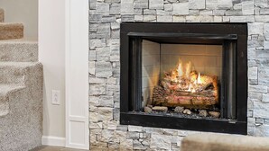 A living room with a stone fireplace, a flat-screen TV mounted above it, and a staircase leading to an upper level. - Center Hill Serenity (Silver Point)