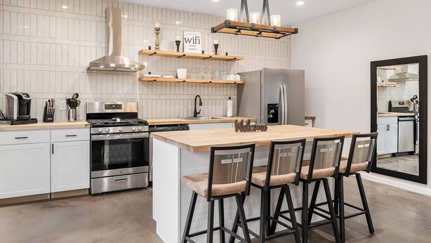 A modern kitchen with a central island, stainless steel appliances, and a hanging light fixture. - Center Hill Serenity (Silver Point)