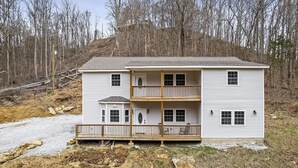 A two-story house with a balcony on the second floor, a small porch on the first floor, and a gravel driveway. - Center Hill Serenity (Silver Point)
