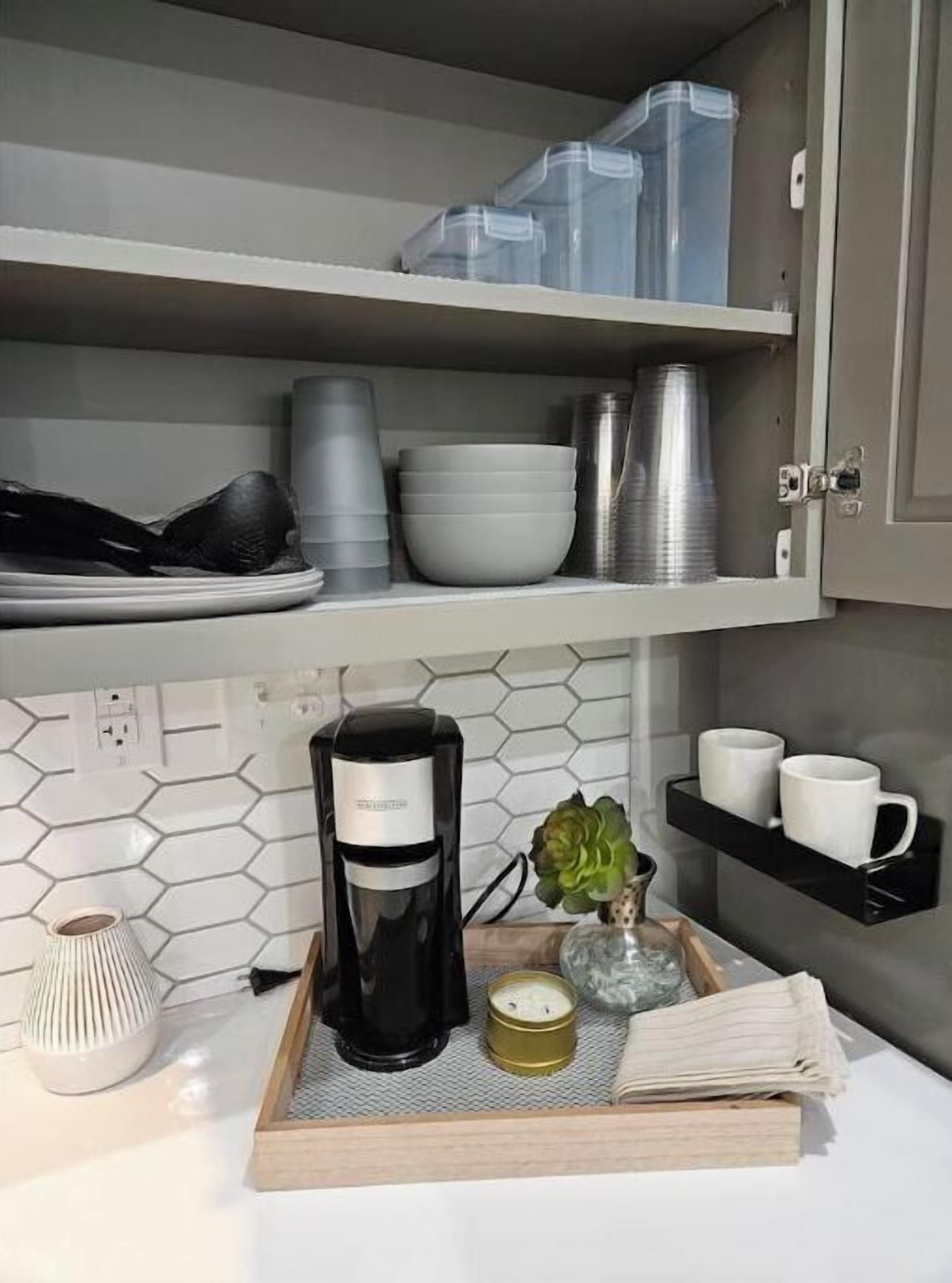 A kitchen with a coffee maker, a tray with a book, a candle, and a small plant.