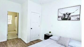 A bedroom with a bed, a ceiling fan, a door, and a wall-mounted picture.