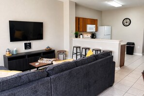 Un salon moderne avec un grand téléviseur à écran plat, un canapé et une petite table basse.