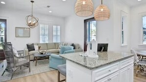 A spacious living area with a large window, a sofa, a coffee table, and a dining table. - Amazing Moonlight Escape- (Panama City Beach)