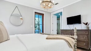 A bedroom with a bed, a dresser, a TV, and a chandelier. - Amazing Moonlight Escape- (Panama City Beach)