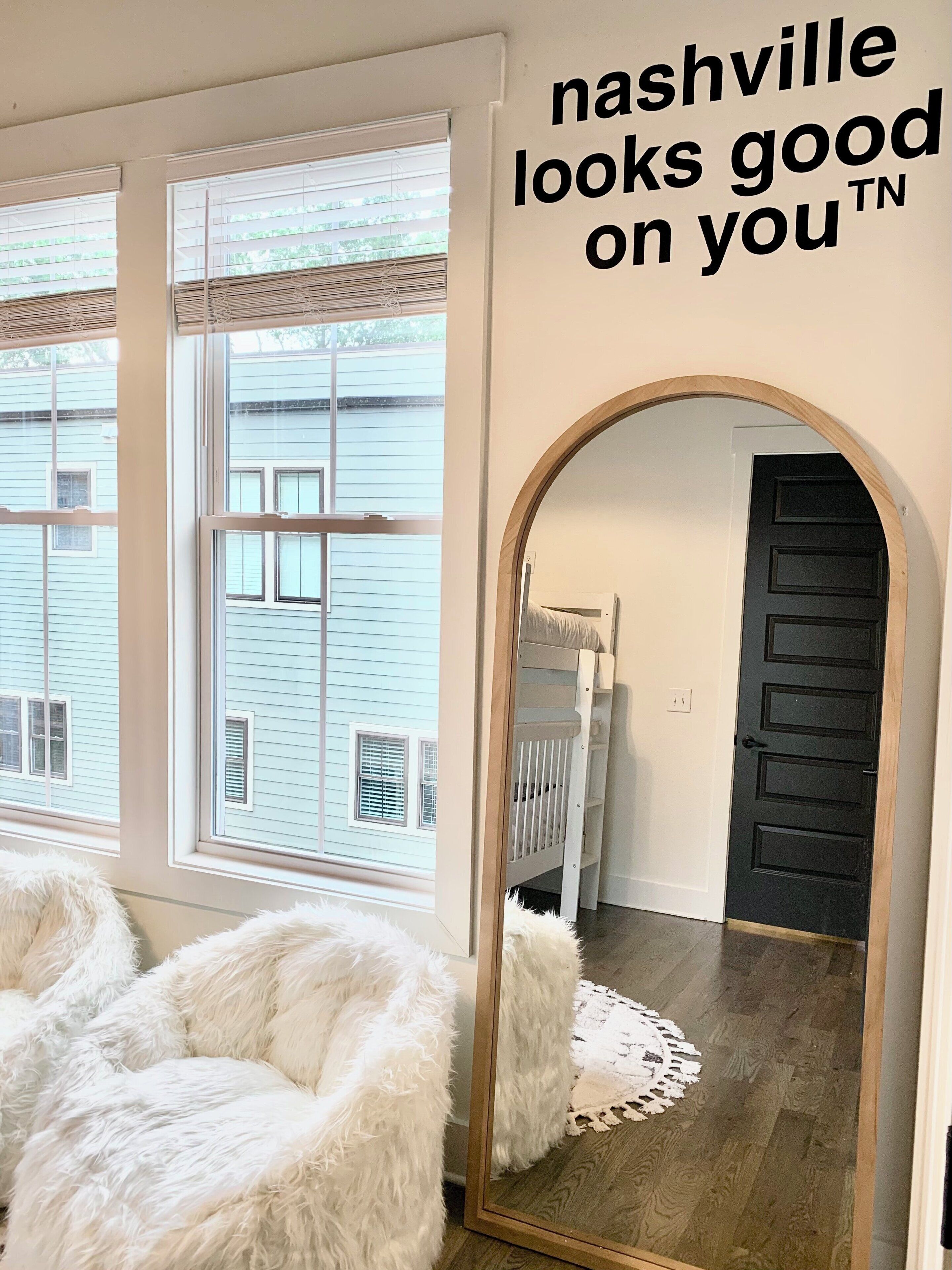 Une pièce dotée de grandes fenêtres, d’un miroir et d’une porte.