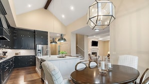 A modern kitchen with dark cabinets, a central island, and pendant lighting. - Modern Farmhouse steps from Momentary and MTB Trails. (Bentonville)