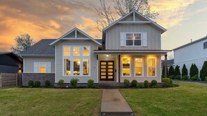 A two-story house with a front porch, a driveway, and a well-maintained lawn. - Modern Farmhouse steps from Momentary and MTB Trails. (Bentonville)