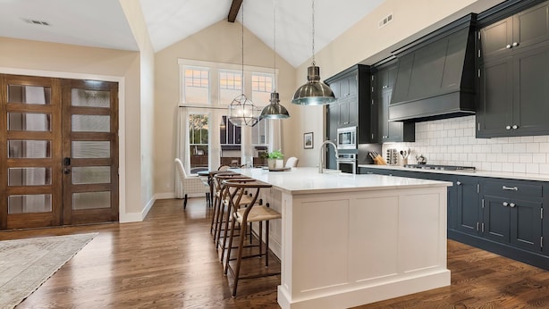 A spacious kitchen with dark cabinets, a large island, and hanging pendant lights. - Modern Farmhouse steps from Momentary and MTB Trails. (Bentonville)