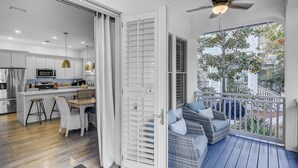 Een moderne keuken met roestvrijstalen apparatuur, een eethoek met rieten meubels en een balkon met uitzicht op de omgeving.