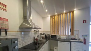 A modern kitchen with white cabinets, a stainless steel range hood, a microwave, and a toaster. - Urban 44 Guest House<br> (Ponta Delgada)