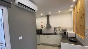 A modern kitchen with white cabinets, a black countertop, and a stainless steel range hood. - Urban 44 Guest House<br> (Ponta Delgada)