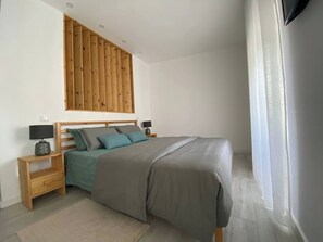 A bedroom with a bed, wooden headboard, nightstands, and a window with curtains. - Urban 44 Guest House<br> (Ponta Delgada)