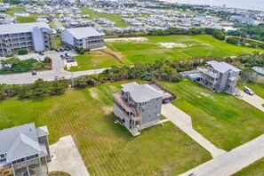 An aerial view of a residential area with multiple buildings, including a large multi-story structure with a flat roof and a smaller building with a sloped roof.