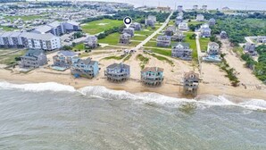 Vista aérea de uma área residencial costeira com casas construídas sobre palafitas na praia.
