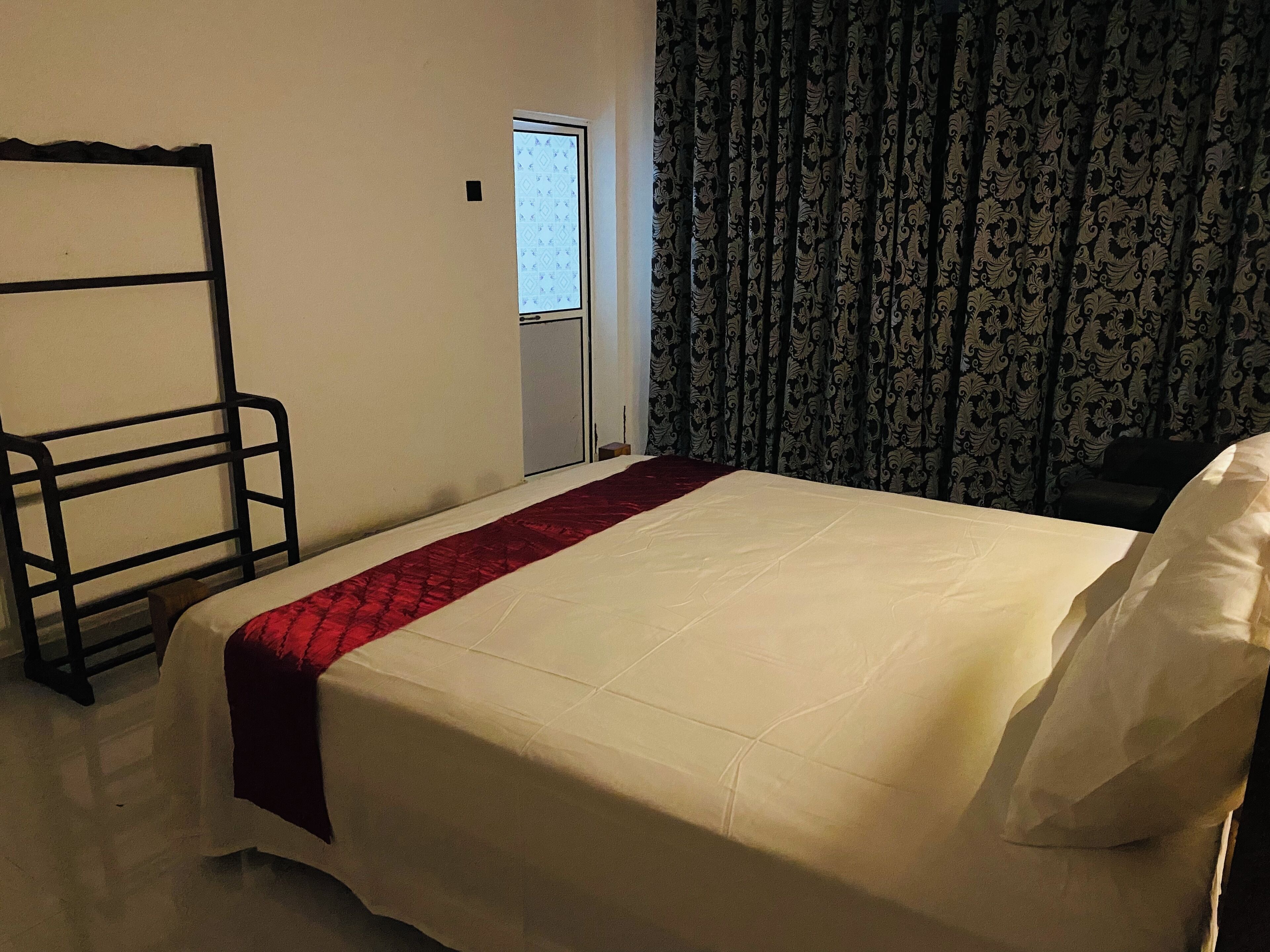 A hotel room with a bed, a wardrobe, and a window with curtains.