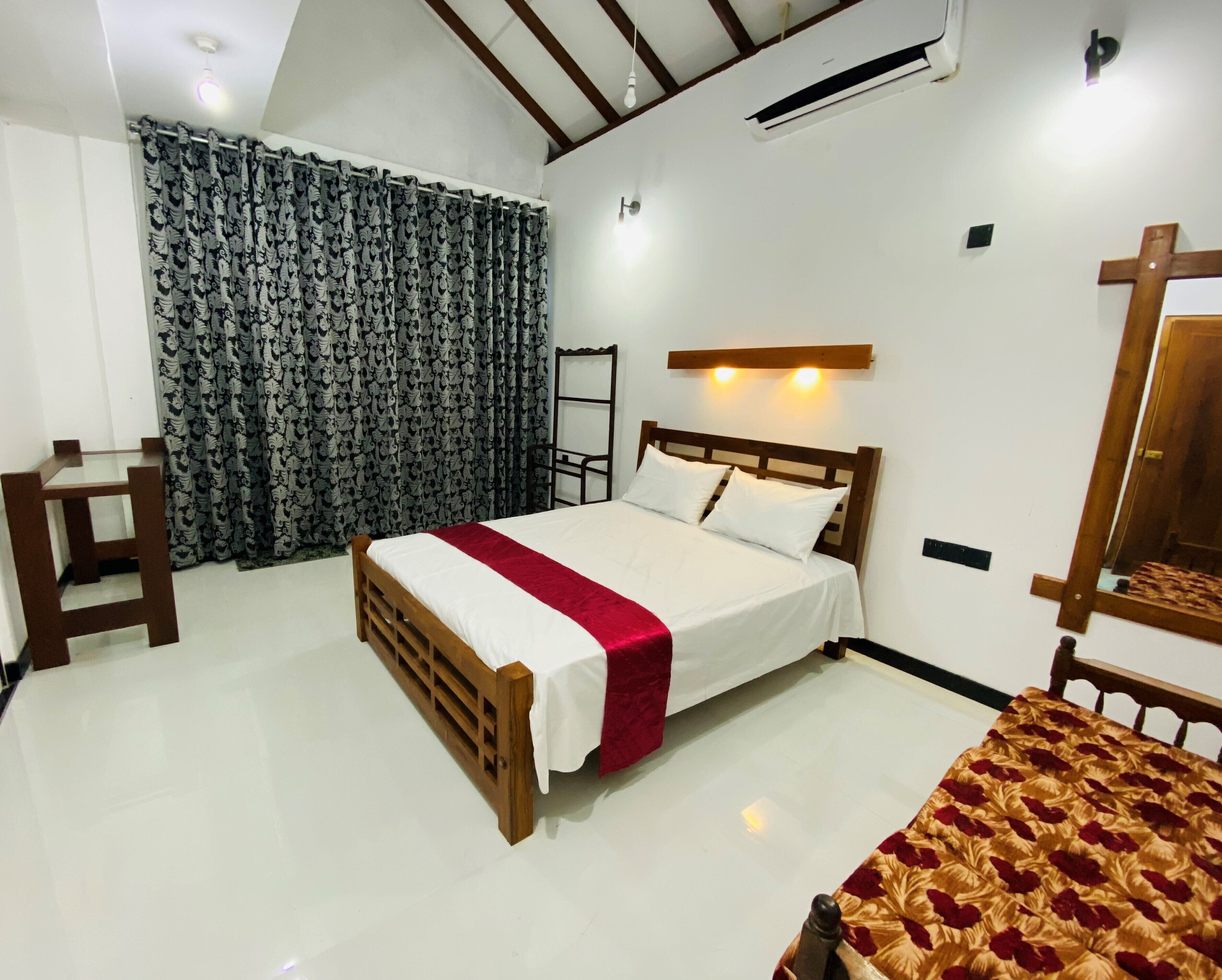 A bedroom with a bed, a wooden chair, a desk, a wardrobe, and a ceiling fan.