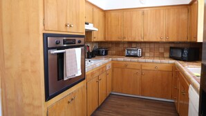 Une cuisine avec des meubles de rangement en bois, un four encastré, un four à micro-ondes et un grille-pain.