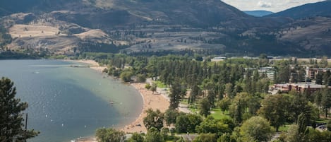 Un pueblo costero con playa, montañas al fondo y una combinación de edificios residenciales y comerciales.