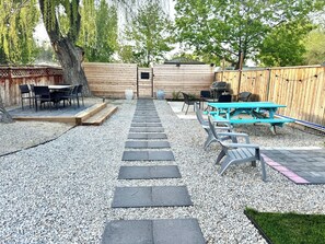 A backyard with a patio area, a barbecue grill, and a picnic table.