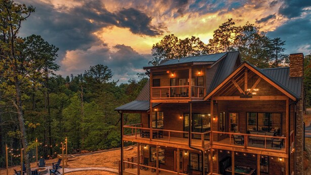 A two-story log cabin with multiple balconies, outdoor seating, and a fireplace.