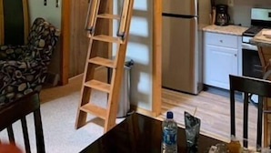 Una cocina con una escalera de madera, una araña y un refrigerador.