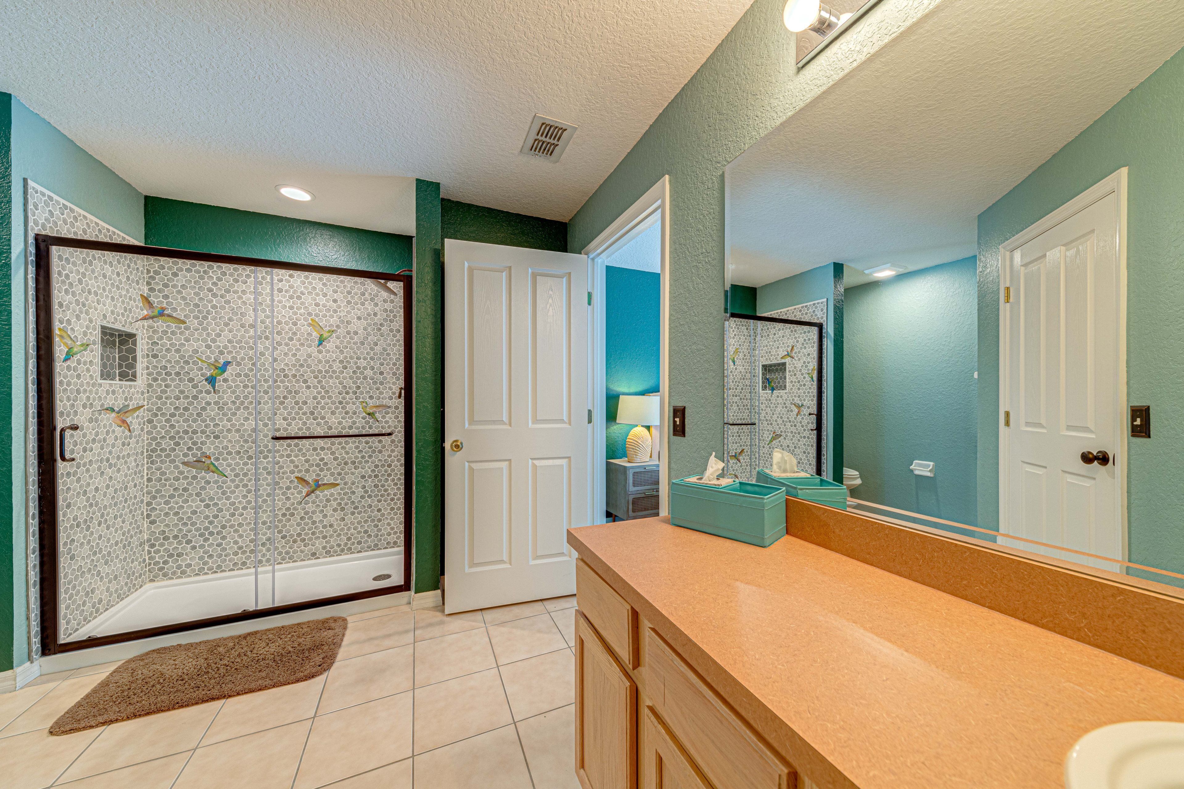 A bathroom with a shower, a sink, and a mirror.